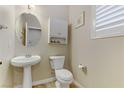 Neat half bathroom with pedestal sink, tile floors, toilet, and a decorative cabinet at 1053 Hickory Park St, Las Vegas, NV 89138