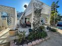 Landscaped exterior with a covered patio, stylish furniture, and trellis with climbing greenery at 6171 Whispering Sands Dr, Las Vegas, NV 89131