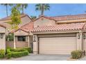 Charming townhome featuring a two-car garage, Spanish tile roof, and manicured landscaping at 7131 Mission Hills Dr, Las Vegas, NV 89113