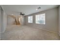 Open-concept living area featuring neutral carpet, staircase, ceiling fan, and bright natural light at 8348 Mokena Ave, Las Vegas, NV 89178