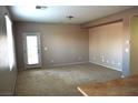 A well-lit living room featuring neutral carpet, walls and an exit door at 8348 Mokena Ave, Las Vegas, NV 89178