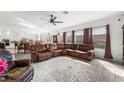 Spacious living room with a ceiling fan, large windows, and a leather sofa perfect for relaxation at 8415 Iron Heart Ln, Las Vegas, NV 89113