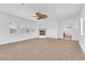 Spacious living room with neutral carpet, large windows, fireplace and arched doorway to another room at 9788 Altadena St, Las Vegas, NV 89183