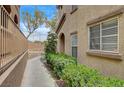 Exterior walkway with green bushes in front of a light brown stucco building at 10270 Gilmore Canyon Ct # 202, Las Vegas, NV 89129