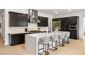 Spacious kitchen with white waterfall island, stainless steel appliances, dark cabinets, and marble backsplash at 135 Barnett Crest Ct, Henderson, NV 89015