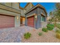 Charming home exterior with three-car garage, beautiful brick driveway, and desert-style landscaping at 28 Vista Outlook St, Henderson, NV 89011