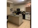 Kitchen featuring white cabinetry, black appliances, a center island with granite countertops and tile flooring at 312 Sierra Breeze Ave, North Las Vegas, NV 89031