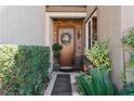 Charming front entrance with a wooden door, stone accents, and lush greenery at 3185 Mura Del Prato Ave, Henderson, NV 89044