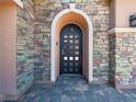 Stylish front door with an arched entryway, multi-colored stone and tiled entryway at 47 Grand Masters Dr, Las Vegas, NV 89141