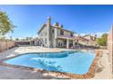 Backyard view of a large swimming pool, patio area, and the back of a two-story home at 8304 Esmont Ln, Las Vegas, NV 89117
