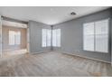 Spacious living room filled with natural light from two large windows, carpet flooring, and neutral paint at 10429 Amber Night St, Las Vegas, NV 89183