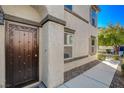 The decorative brown metal front door is surrounded by a beige stucco exterior, complemented by well-maintained landscaping at 1055 Admiral Emblem St, Henderson, NV 89015