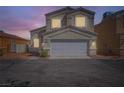 Charming two-story townhome with a two-car garage, showcasing a warm ambiance at twilight at 5252 Mineral Lake Dr, Las Vegas, NV 89122
