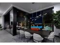 Sleek dining room with modern table, chairs, and expansive windows overlooking a pool and the city lights at 545 Overlook Rim Dr, Henderson, NV 89012