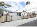 Charming single-story home featuring desert landscaping, black iron fence, and solar panels for energy efficiency at 6170 W University Ave, Las Vegas, NV 89103