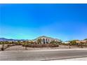 View of the front exterior showcasing the arched entrance, desert landscaping and custom iron gate at 7025 N Eula St, Las Vegas, NV 89149