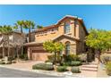 Two-story home with desert landscaping, tan stucco, brick driveway, palm trees and a two-car garage at 1013 Baronet Dr, Las Vegas, NV 89138