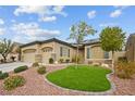 Well-manicured front yard with an artificial lawn, rock landscaping, and mature trees at 10704 Warrior Ct, Las Vegas, NV 89135