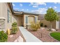 Inviting home entrance with colorful desert landscaping and a paved walkway at 10704 Warrior Ct, Las Vegas, NV 89135