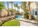 Landscaped backyard featuring a charming pool, stone pathway and mature palm trees at 124 Beach Oak Ave, Henderson, NV 89002