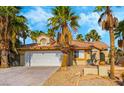 Charming single-story home featuring a two-car garage and mature palm trees, set against a bright blue sky at 124 Beach Oak Ave, Henderson, NV 89002