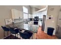 Updated kitchen with white cabinets, granite countertops, stainless steel appliances, and breakfast bar seating at 124 Beach Oak Ave, Henderson, NV 89002