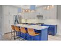 Modern kitchen features a center island with seating, stainless steel appliances, and bright pendant lighting at 2374 Falsetto Ave, Henderson, NV 89052