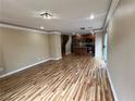 Spacious living room featuring wood floors that seamlessly connects to an open kitchen with sliding door access to the patio at 566 Shewsbury Ave, Las Vegas, NV 89178