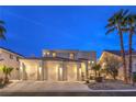 Beautiful two-story stucco home featuring a three-car garage, manicured landscape, and red tile roof at twilight at 8032 Marbella Cir, Las Vegas, NV 89128