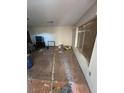 Interior view of a living room in disrepair with damaged floors and a large window at 895 Greasewood Ln, Moapa, NV 89025