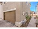Two-story beige home featuring a brown garage door, stucco exterior and manicured landscaping at 1425 Bow Creek Ct, Las Vegas, NV 89128