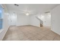 Bright living room with tile flooring, ceiling fan, staircase, and a view of the front door at 5044 Whistling Acres Ave, Las Vegas, NV 89131
