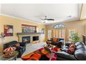A cozy living room with a fireplace, ceiling fan, and comfortable seating at 10892 Royal Highlands St, Las Vegas, NV 89141