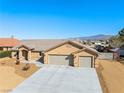 Charming single-story home with a three-car garage, desert landscaping, and extended driveway at 5450 Barnwood Ct, Pahrump, NV 89061
