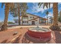 Two-story home featuring a fountain, palm trees, a second story balcony and desert landscaping at 7079 Laredo St, Las Vegas, NV 89117