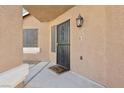 Close up of the home's black, decorative security door, and tan exterior with a welcome mat and front light fixture at 7621 Gosport Ave, Las Vegas, NV 89131