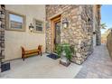 Inviting front porch with stone accents, a bench, potted plants, and decorative lighting at 949 Via Stellato St, Henderson, NV 89011