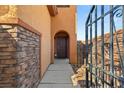 Inviting front entrance with stone accents, arched doorway, and secured gated entry at 10133 Longoria St, Las Vegas, NV 89178