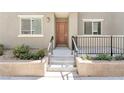 Front porch with steps, metal railing, neutral-colored stucco, and tidy landscaping at 12367 Indigo Montage Rd # 3, Las Vegas, NV 89183
