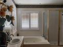 Bright bathroom featuring a jetted tub with white shutters, a glass enclosed shower, and decorative accents at 1255 Del Lilly Ln, Las Vegas, NV 89123