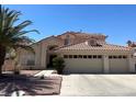 This home has a red tile roof and a three-car garage complemented by a well-kept lawn and mature landscaping at 1255 Del Lilly Ln, Las Vegas, NV 89123