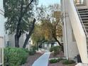 Landscaped pathway between apartment buildings with mature trees and verdant shrubs under a blue sky at 1881 W Alexander Rd # 2095, North Las Vegas, NV 89032