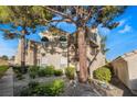 Condominium exterior showcasing mature trees, stucco siding, and lush green landscaping at 2251 Wigwam Pkwy # 923, Henderson, NV 89074