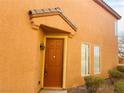 Stylish home entrance with a classic brown door, rustic light fixture, and manicured shrubbery at 3525 Hammock St, Las Vegas, NV 89147