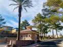 Community guard house near the entrance to the neighborhood surrounded by trees and lush landscaping at 3525 Hammock St, Las Vegas, NV 89147