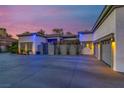 Striking home exterior showcasing a spacious driveway, three-car garage, tasteful landscaping and dramatic accent lighting at dusk at 7436 Oak Grove Ave, Las Vegas, NV 89117