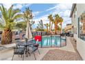Lovely backyard oasis with a pool, outdoor dining set, and lush palm trees create a serene retreat at 1486 Neyland Dr, Henderson, NV 89012