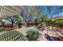 Lush backyard with mature trees, rock features, and an open patio area at 2309 Aztec Ruin Way, Henderson, NV 89044