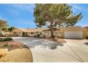 Inviting single-level home with mature trees, rock landscaping, and a wide driveway leading to the garage at 4795 W Maulding Ave, Las Vegas, NV 89139