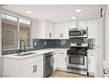 Modern kitchen with stainless steel appliances, white cabinets, and blue backsplash at 2793 Sandyfalls Way, Las Vegas, NV 89142